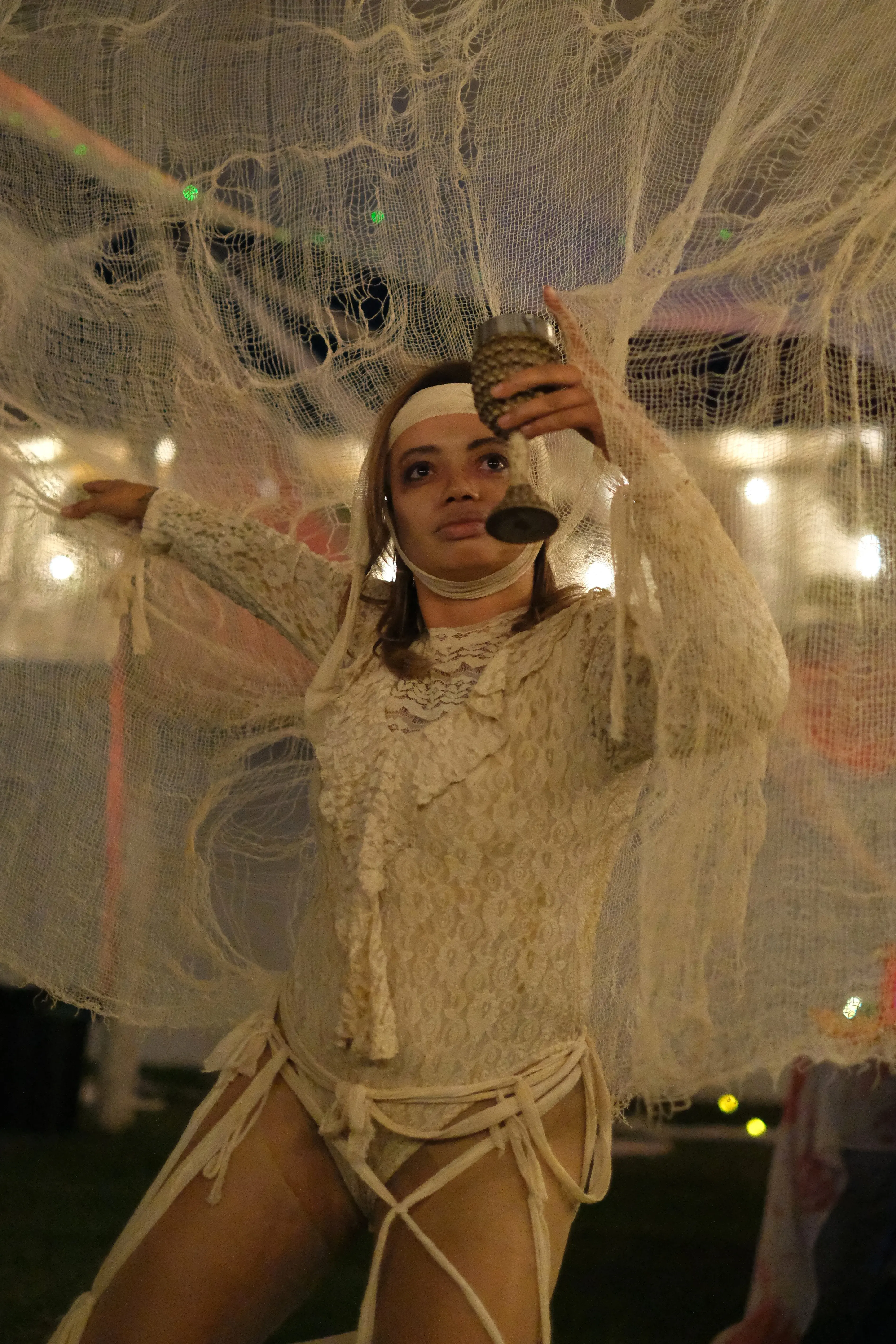 A guest in a white lace costume raises a goblet beneath gauze decorations.