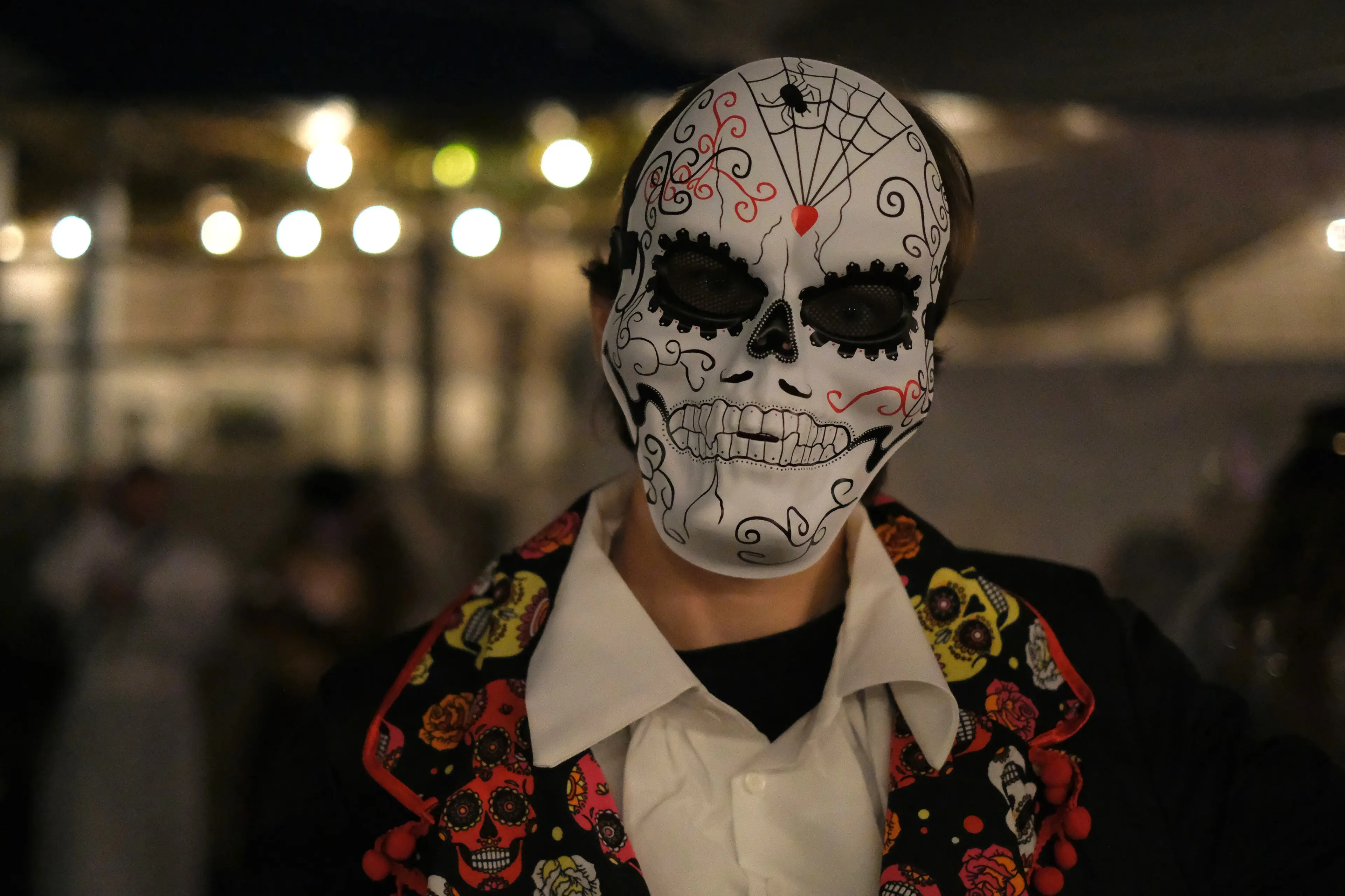 A guest wears an ornate skull mask and a colourful embroidered jacket.